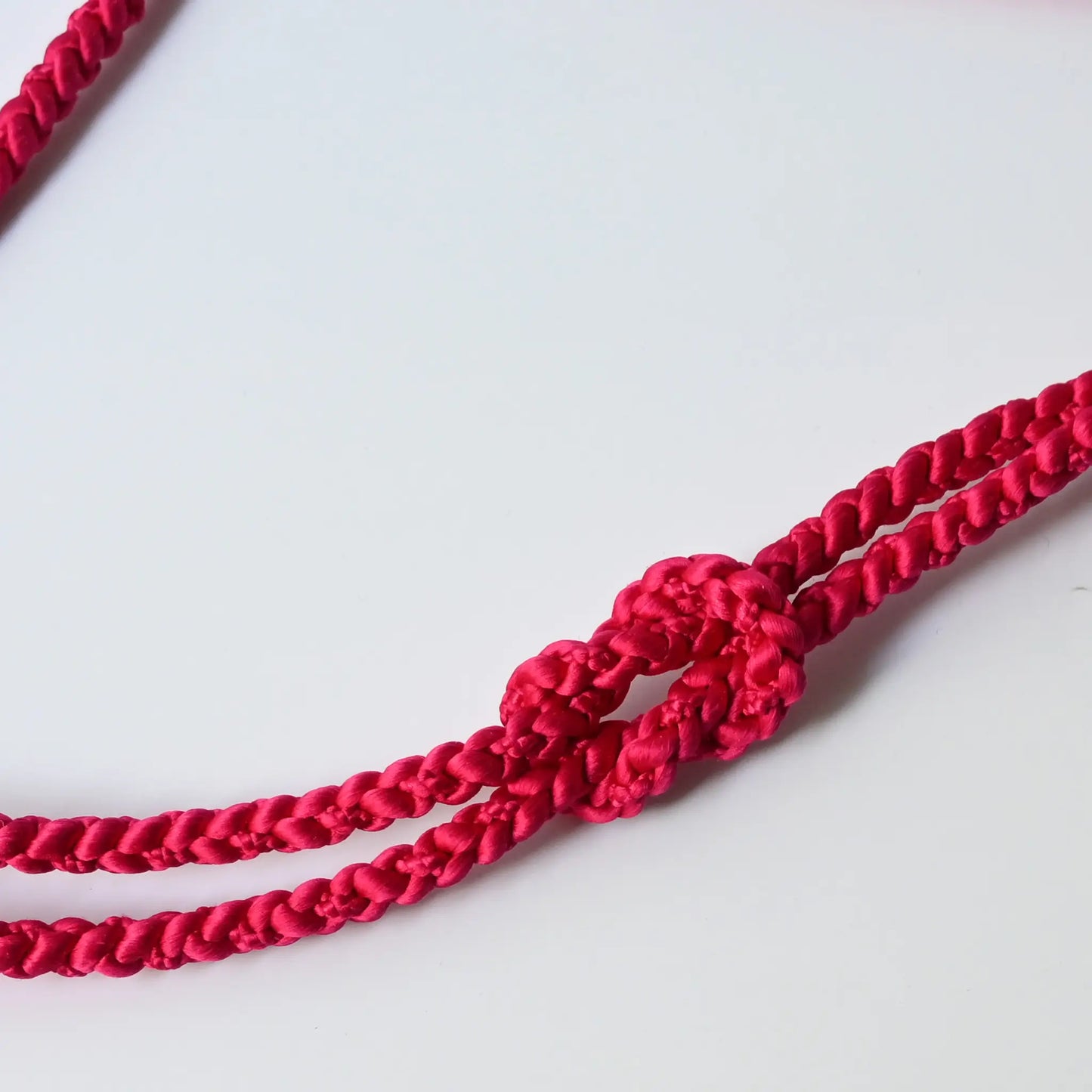Close-up of recycled silk obijime braided cord in a striking dark hot pink.