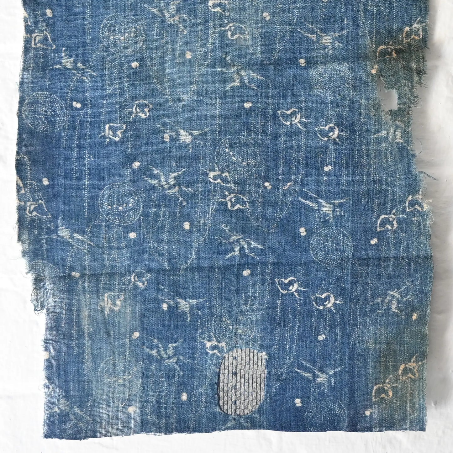 Close-up view of fragment of antique indigo katazome cotton with small patters of plover, willow, tamari ball and crane, late 19th century to early 20th century.