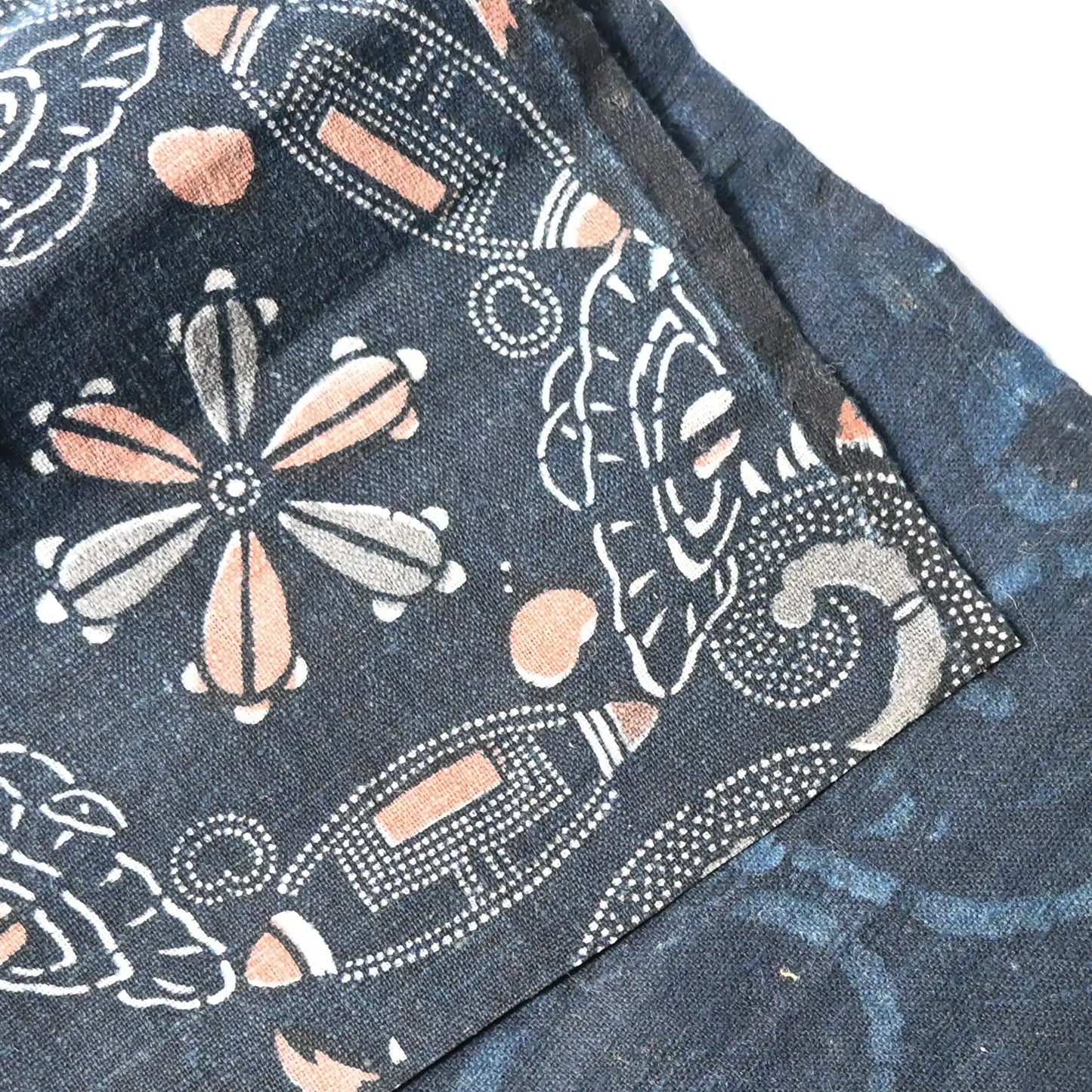 Close-up view of antique indigo katazome dyed cotton piece with abstract floral motif, indigo with Bengala red and grey accents.