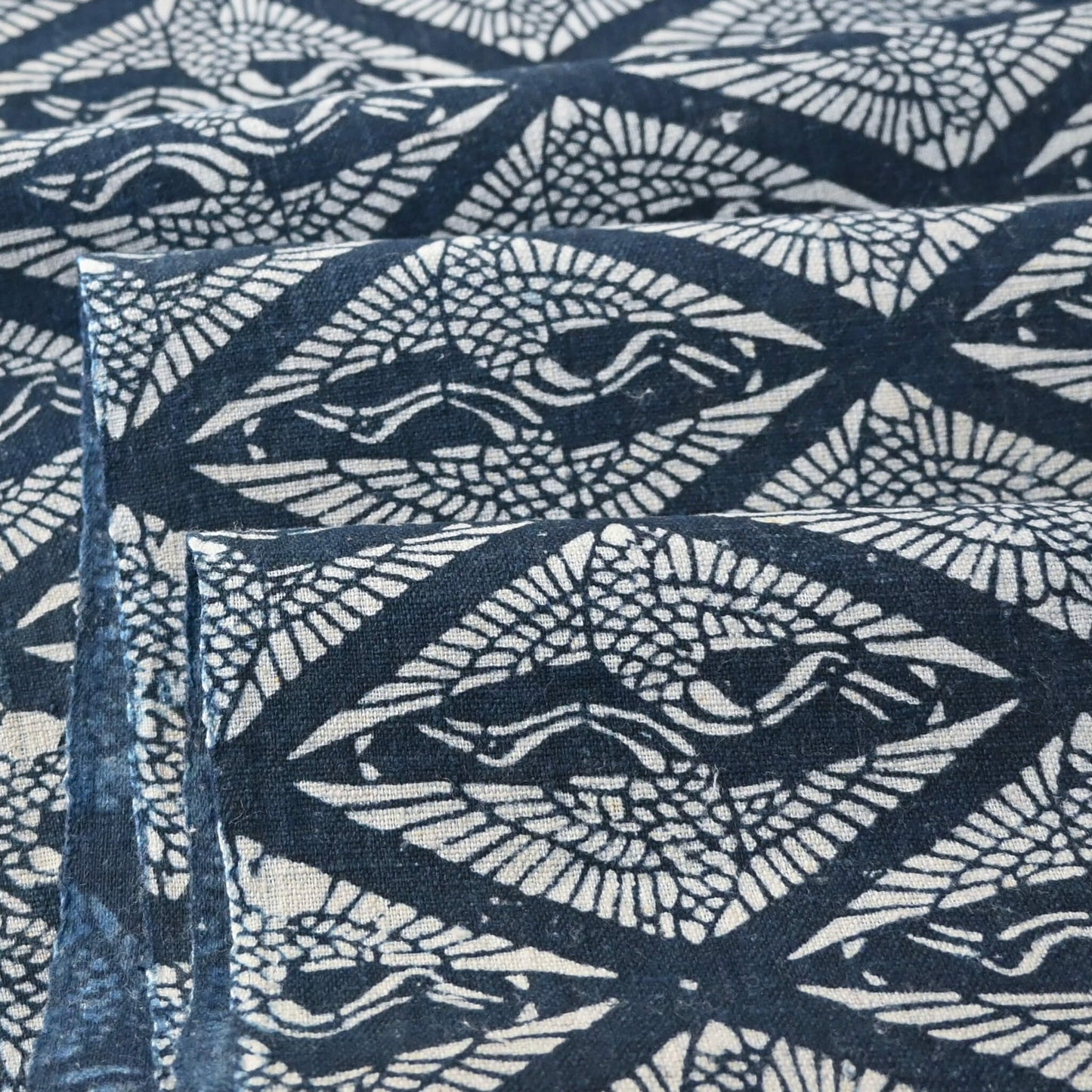 Cloe-up view of antique Japanese indigo katazome dyed cotton with a repeating pattern of paired cranes within diamond-shaped motifs.