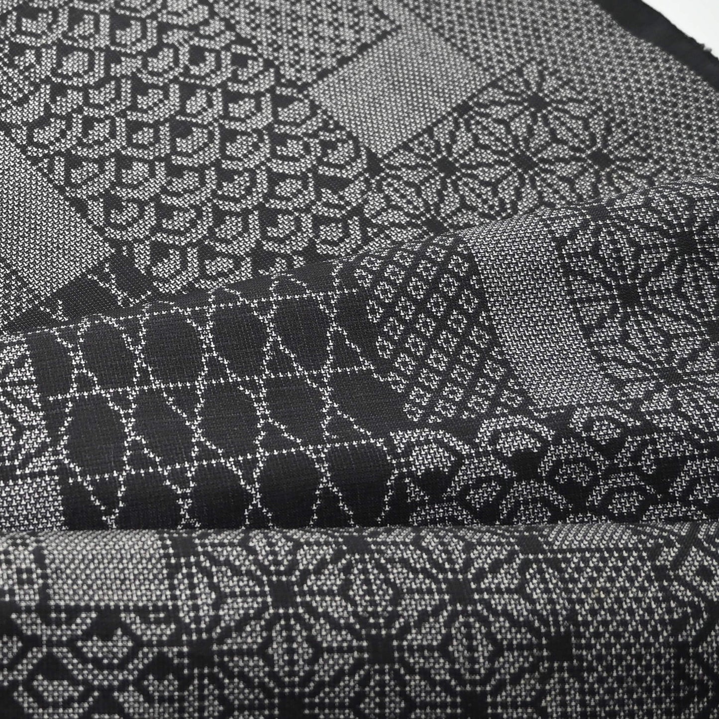 Close-up view of vintage black silk kimono fabric roll with patchwork-style geometric pattern, sold by the metre.