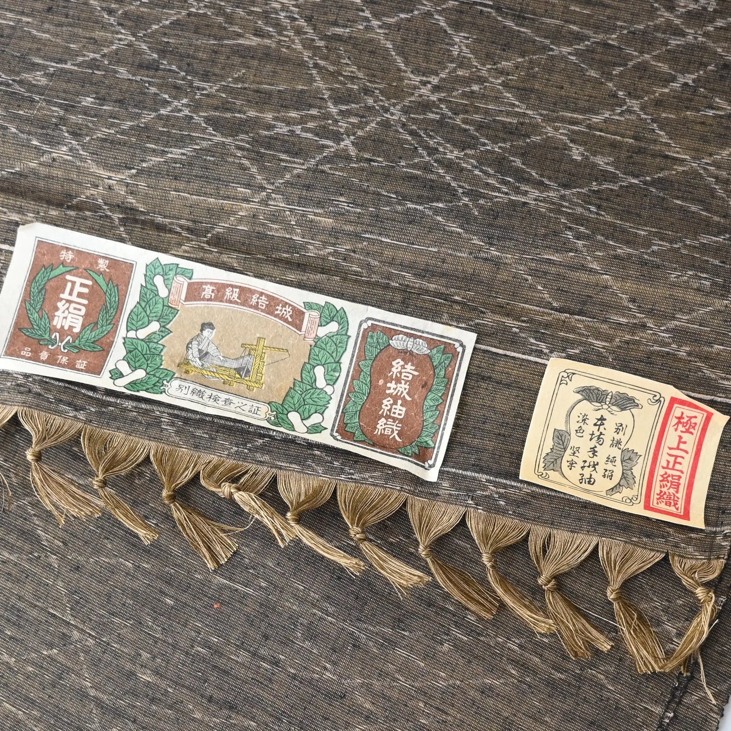 Detailed view of vintage Yuki tsumugi silk kimono fabric in brown and khaki-green tone with autumn grasses motif.