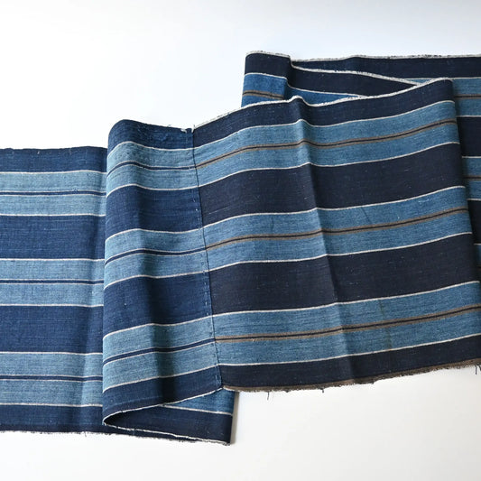 Full view of vintage indigo stripe cotton from a futon cover, two different stripe patterns joined together with mended patches.