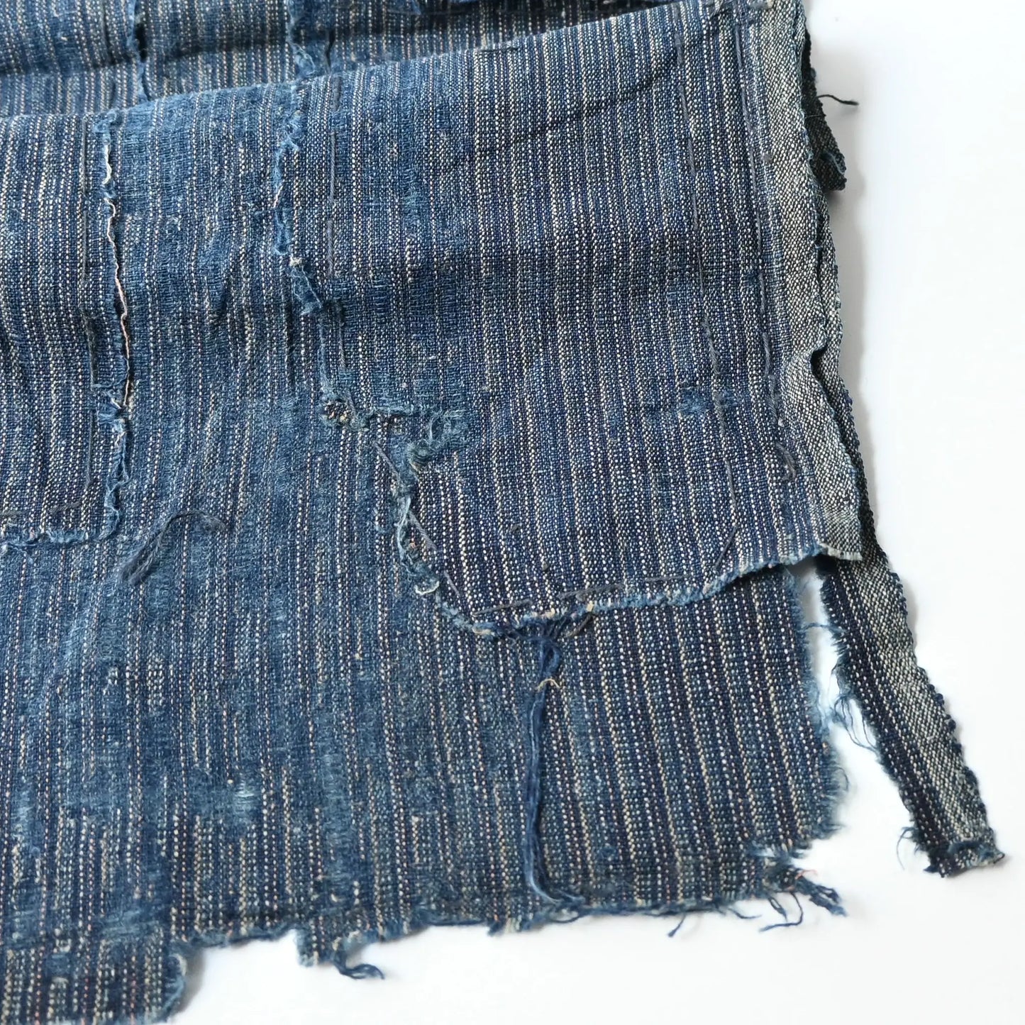 Detailed view of vintage Japanese fragment of indigo fine stripe cotton boro with wear.