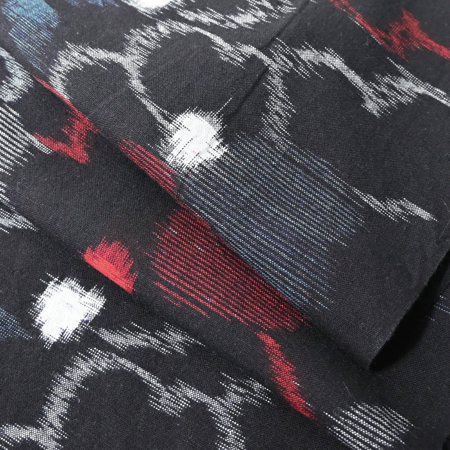 Close-up view of vintage indigo kasuri cotton kimono fabric with bold floral pattern in red and blue.