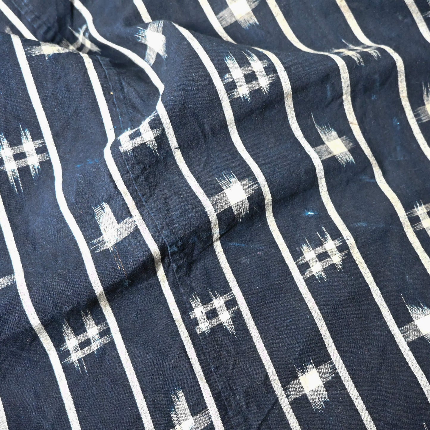 Close-up view of vintage three-panel indigo kasuri cotton furoshiki with hand stitched botanical motifs on the corner.