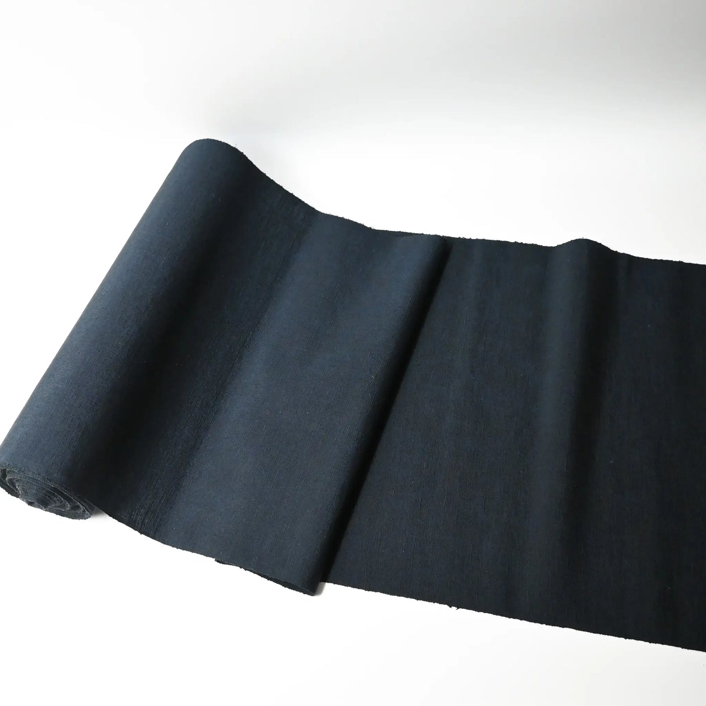Full view of vintage dead stock men's tsumugi silk kimono fabric roll in dark sea tone.