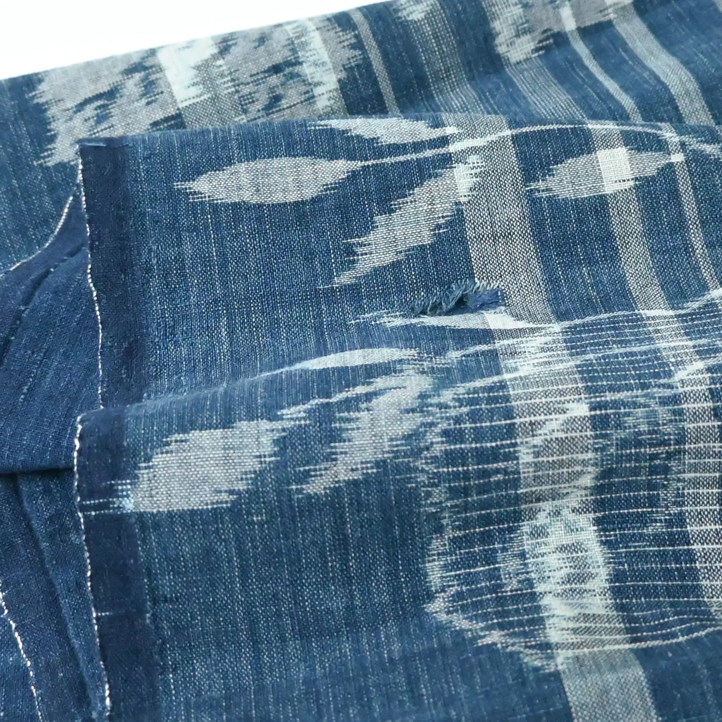 Vintage Japanese indigo egasuri cotton from the early 20th century in pre-loved condition with a hole.