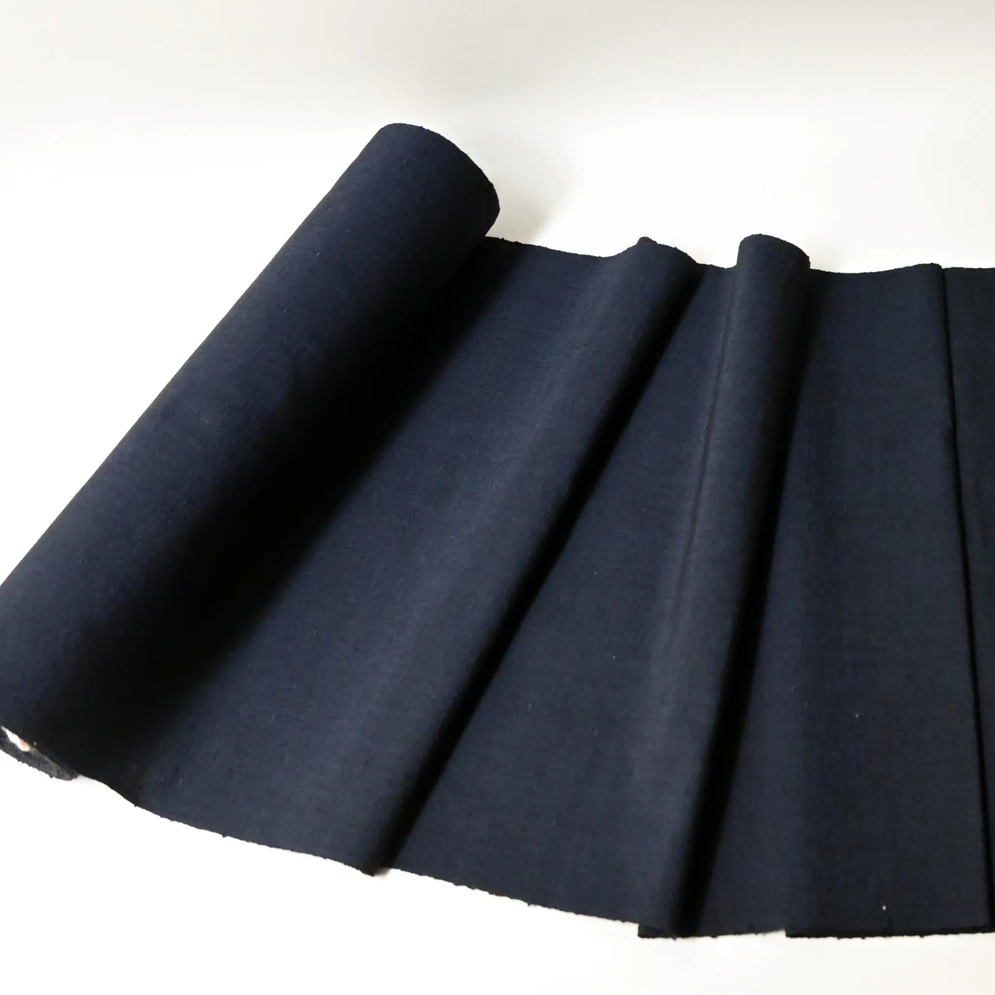Full view of vintage dead stock men's tsumugi silk kimono fabric roll in navy blue.