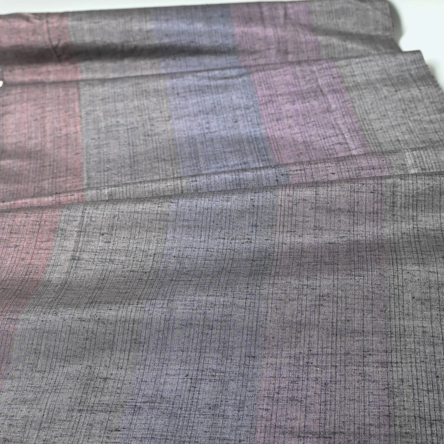 Close-up view of vintage lilac grey tsumugi silk kimono fabric.