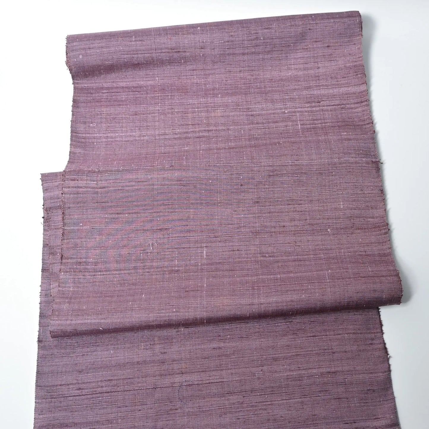 Full view of vintage lilac tsumugi silk kimono fabric roll with textured slubs.