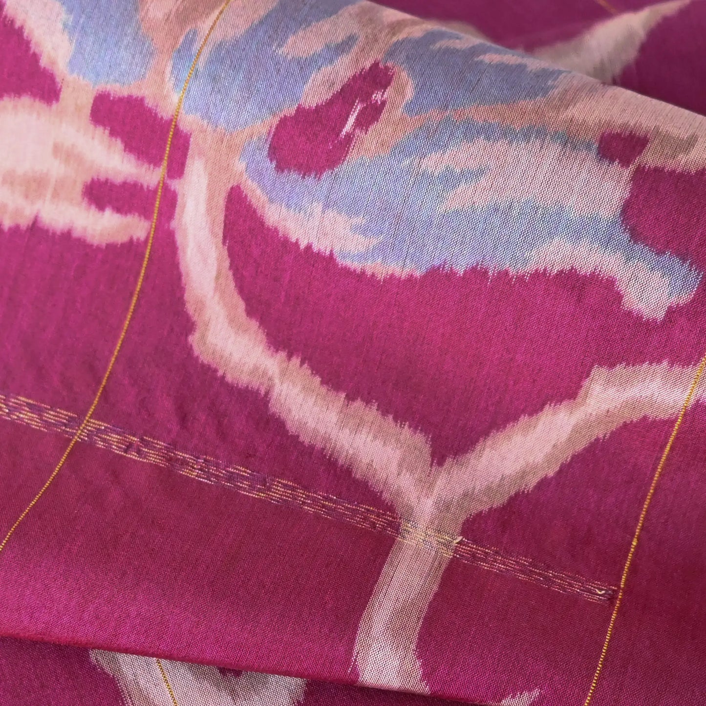 Close-up view of Vintage Meisen kimono silk fabric, magenta colour with light blue floral pattern, ikat woven.
