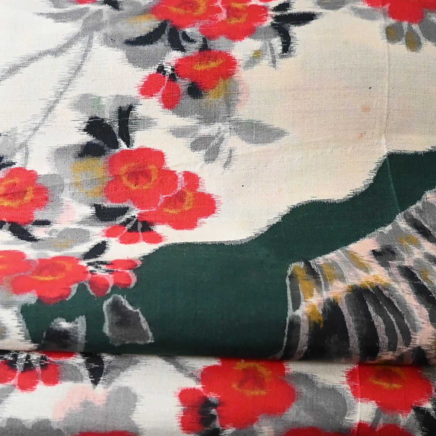 Close-up view of vintage women's meisen silk kimono fabric piece with red plum blossom motif.