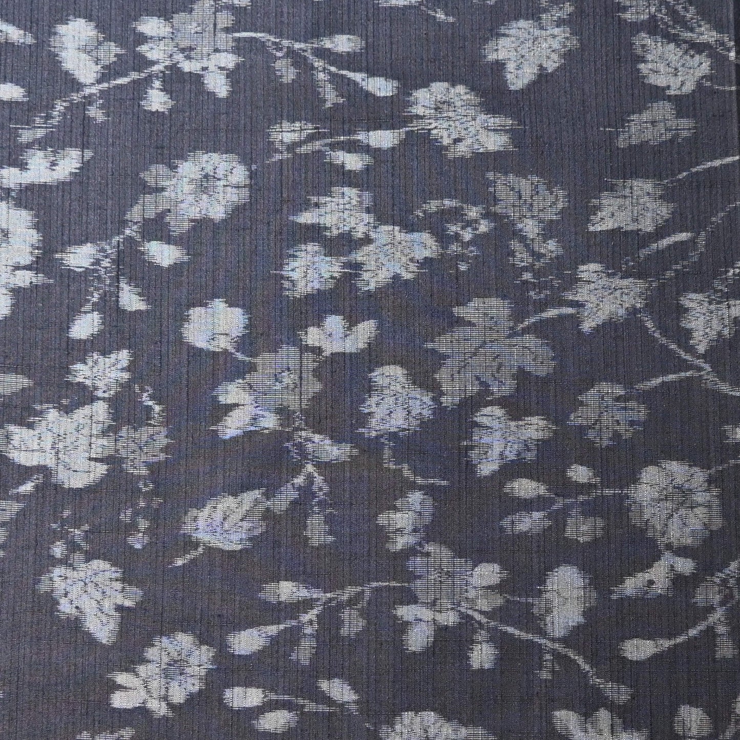 Close-up view of vintage tsumugi silk kimono fabric with silver grey vine floral pattern on a navy ground.