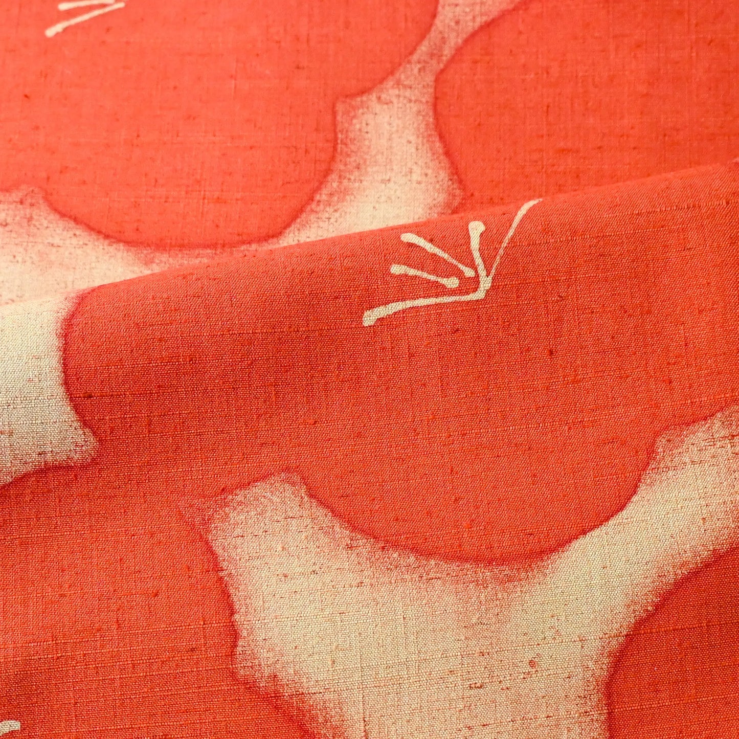 Detailed view of vintage Japanese tsumugi silk kimono fabric piece in reddish orange with bold plum blossom.