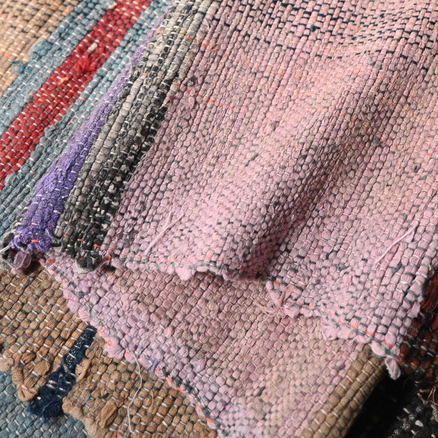 Close-up view of vintage Sakiori fragment cloth from Tohoku region, woven from shredded strips of recycled kimono and futon covers.