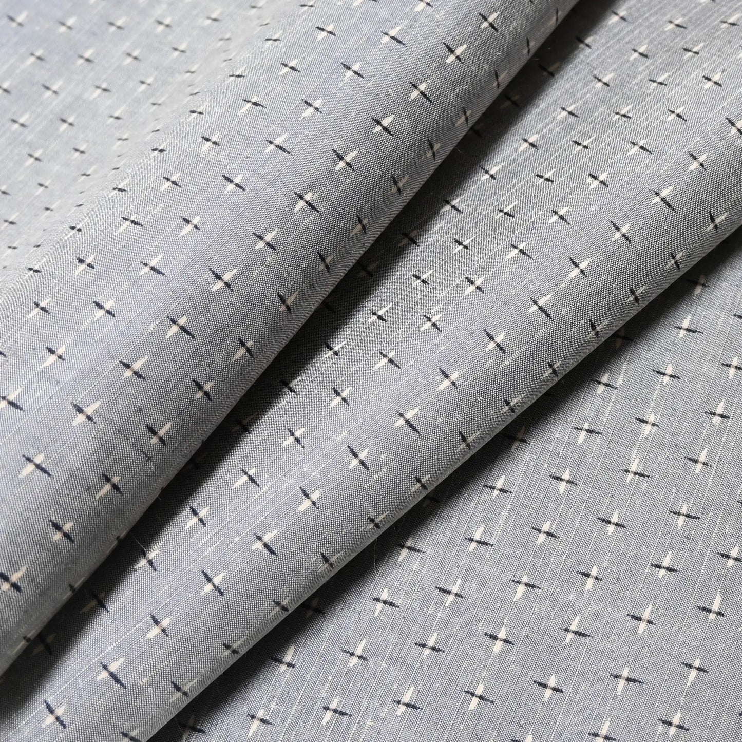 Close-up view of vintage soft blue-grey tsumugi kimono silk with small kasuri crosshatch pattern.