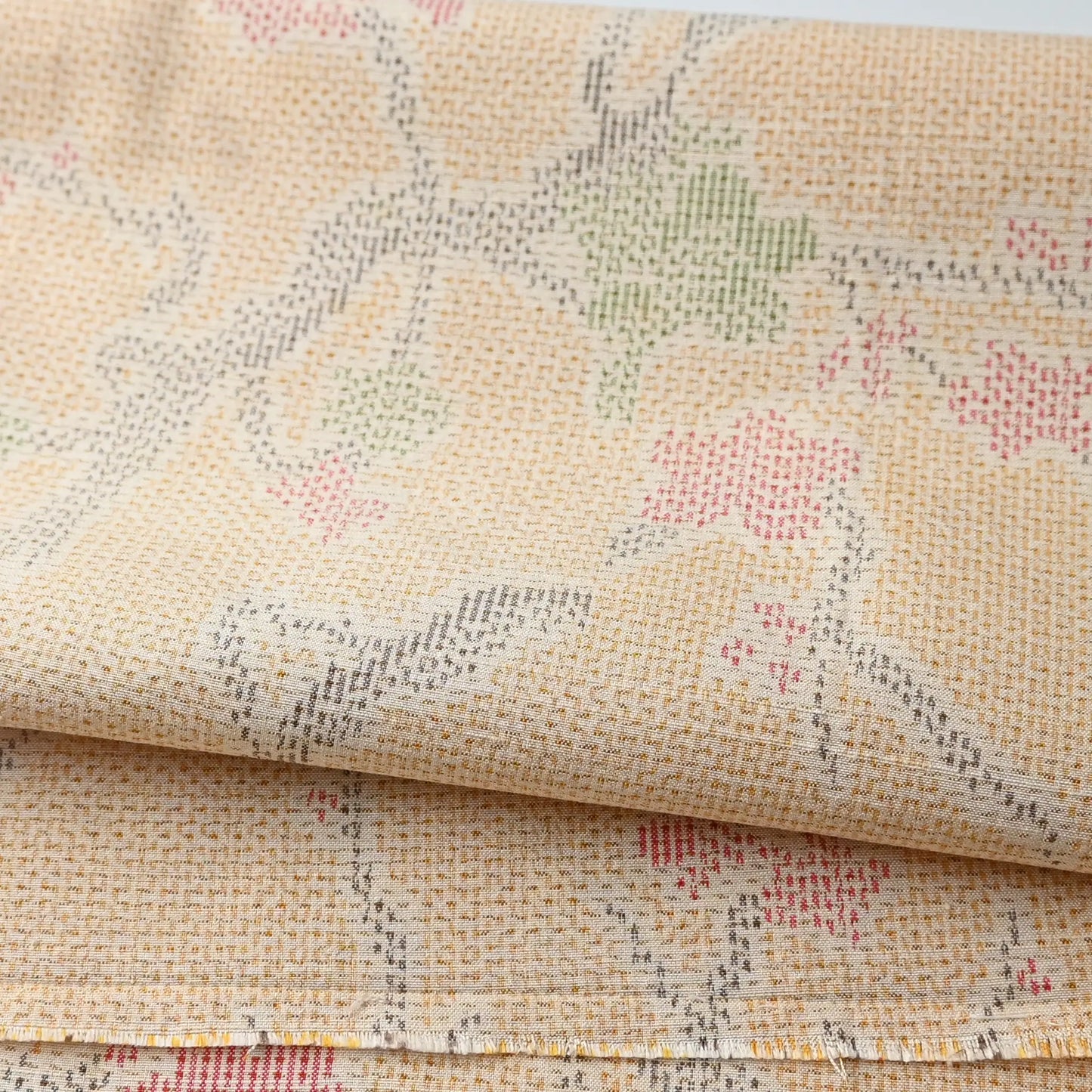Detailed view of vintage soft yellow tsumugi kimono silk fabric piece with plum blossom pattern.
