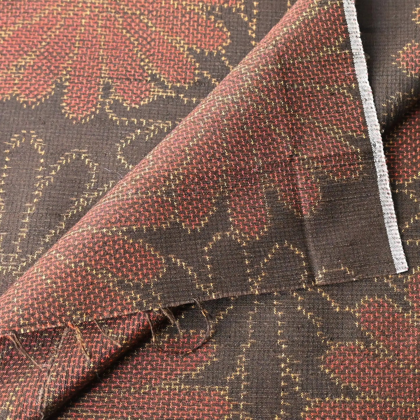 Detailed view of vintage brown tusmugi kimono silk fabric piece with chrysanthemum motif.