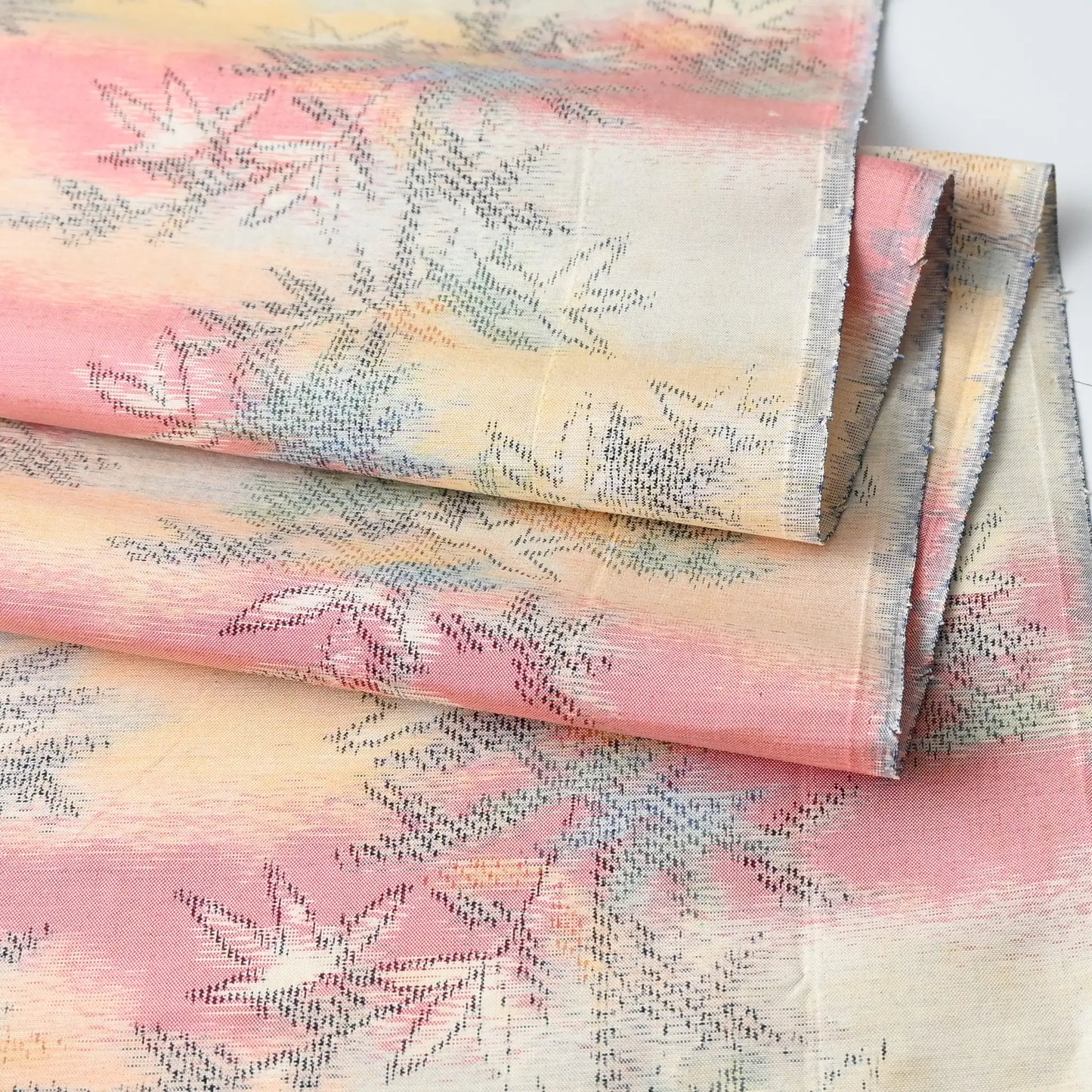 Detailed view of vintage tsumugi silk kimono fabric piece in soft yellow and pink with bamboo motif.