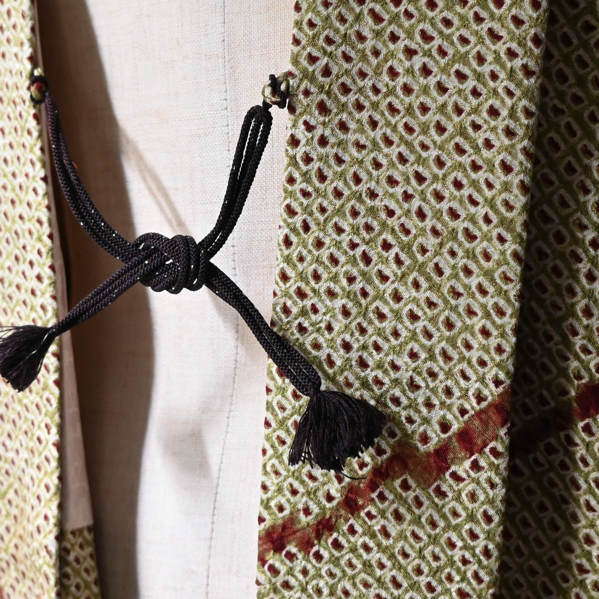 Close-up view of vintage women's silk shibori haori with an olive green and reddish-brown all-over pattern.
