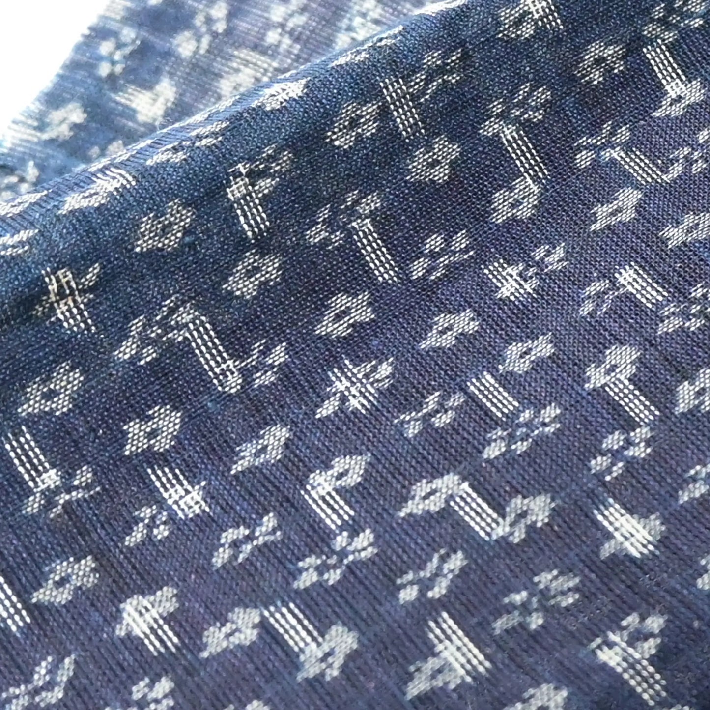 Close-up view of antique indigo Kasuri hemp with intricate floral pattern, originally an apron.