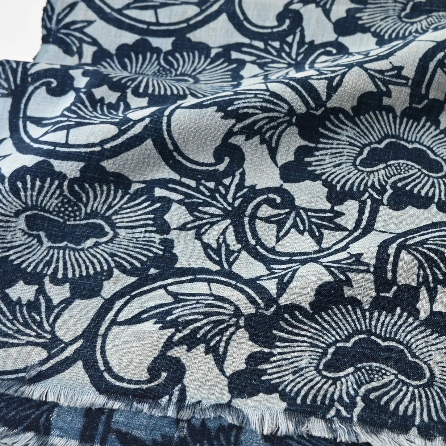 Close-up view of antique indigo katazome cotton with peony arabesque motif in layered indigo tones.