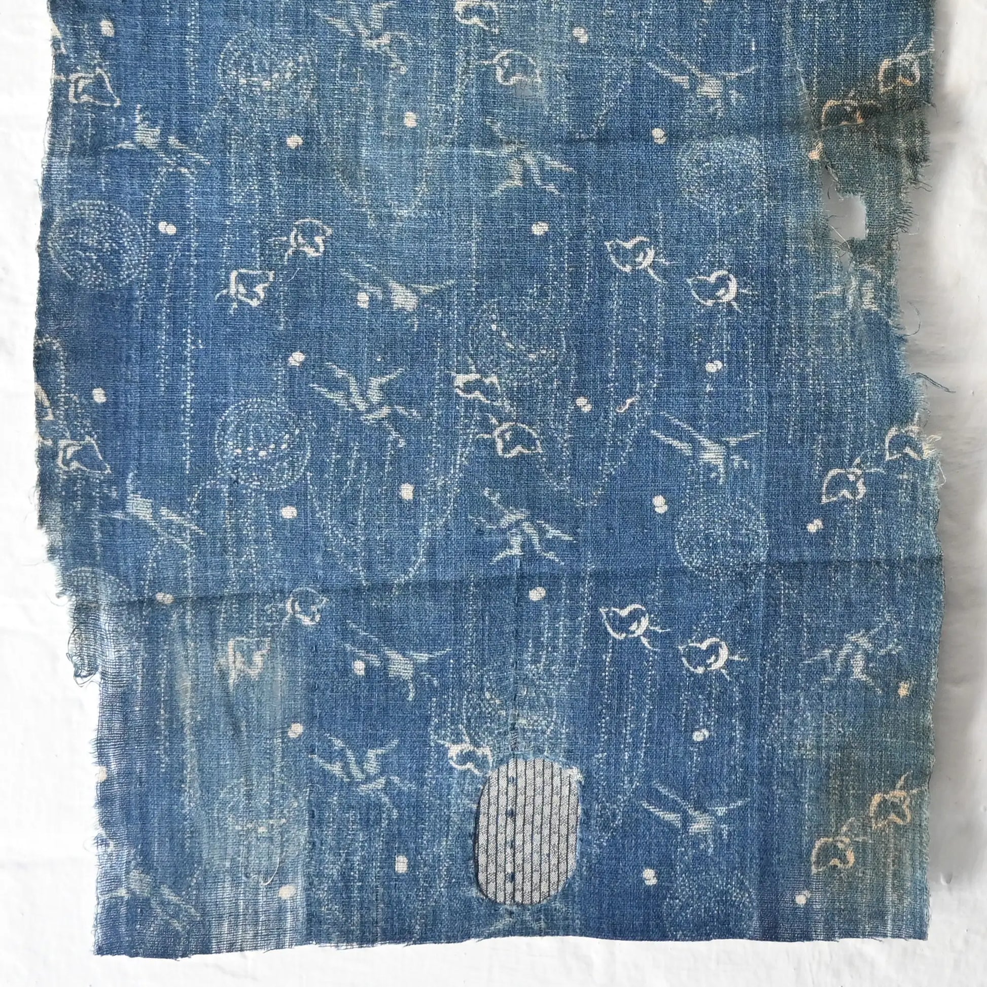 Close-up view of fragment of antique indigo katazome cotton with small patters of plover, willow, tamari ball and crane, late 19th century to early 20th century.