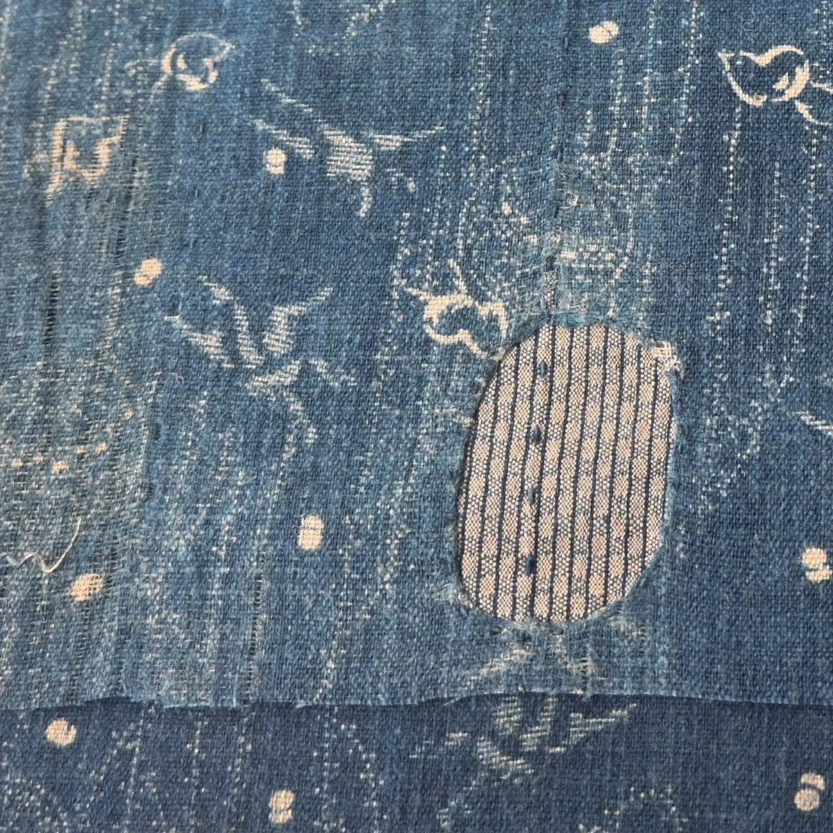 Close-up view of fragment of antique indigo katazome cotton with small patters of plover, willow, tamari ball and crane, late 19th century to early 20th century.