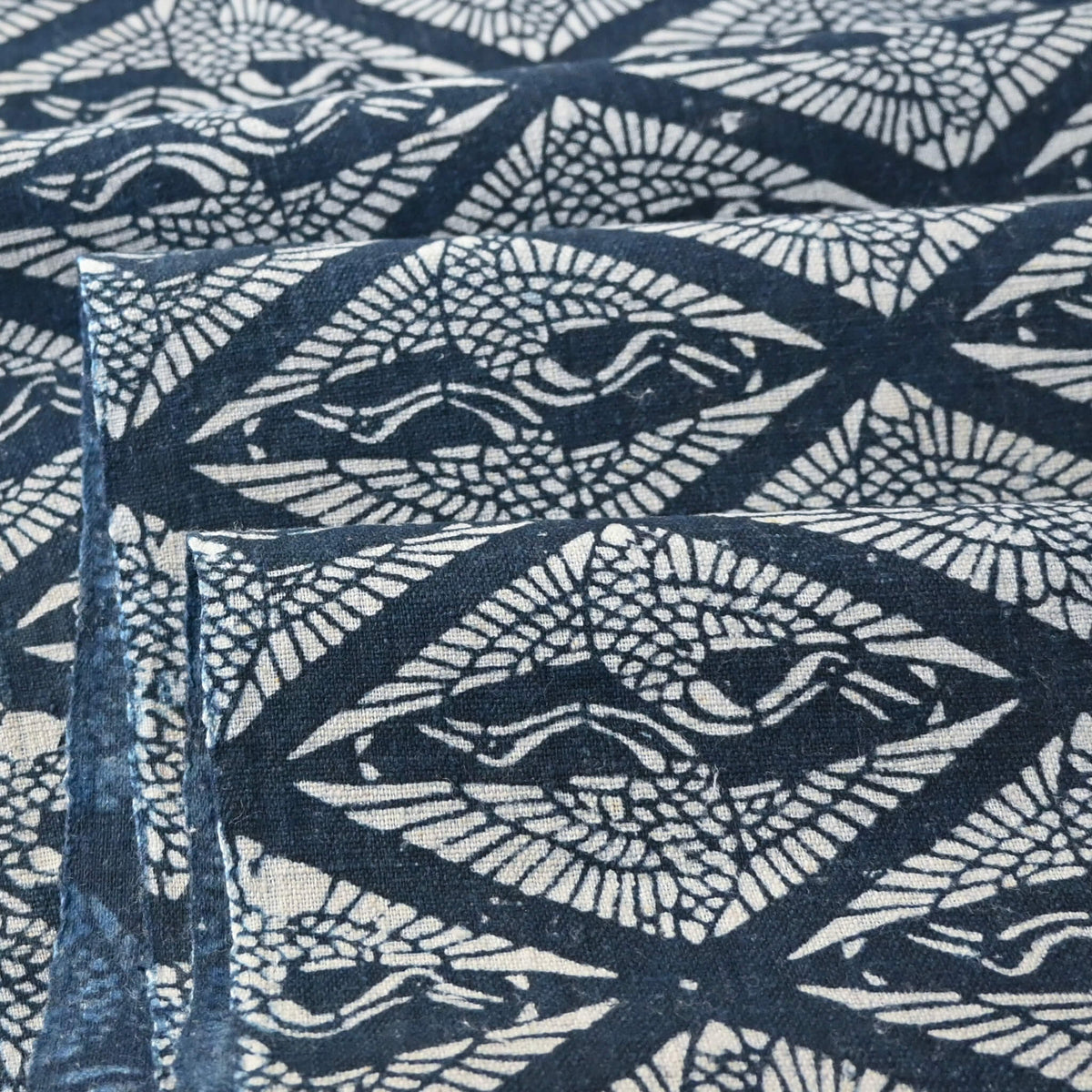 Cloe-up view of antique Japanese indigo katazome dyed cotton with a repeating pattern of paired cranes within diamond-shaped motifs.