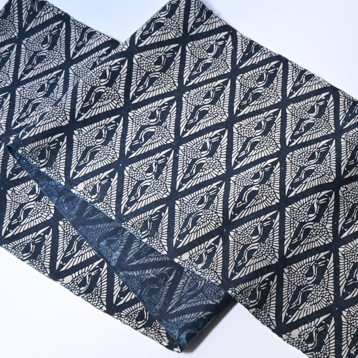 Antique Japanese indigo katazome dyed cotton with a repeating pattern of paired cranes within diamond-shaped motifs.