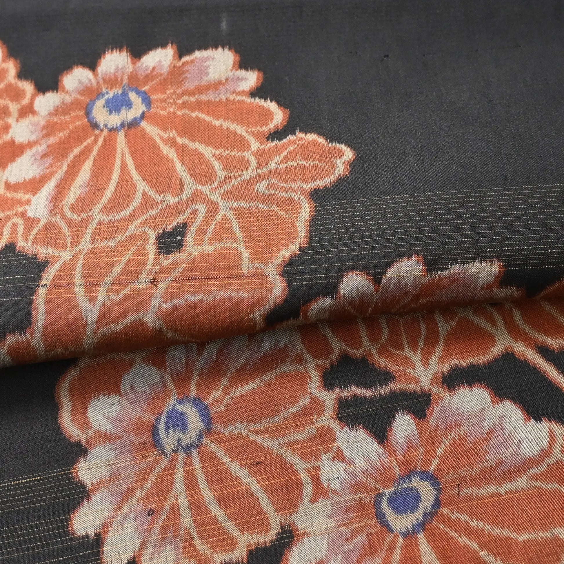 Detailed view of antique Japanese black lightweight fine silk kimono fabric with chrysanthemum motif.