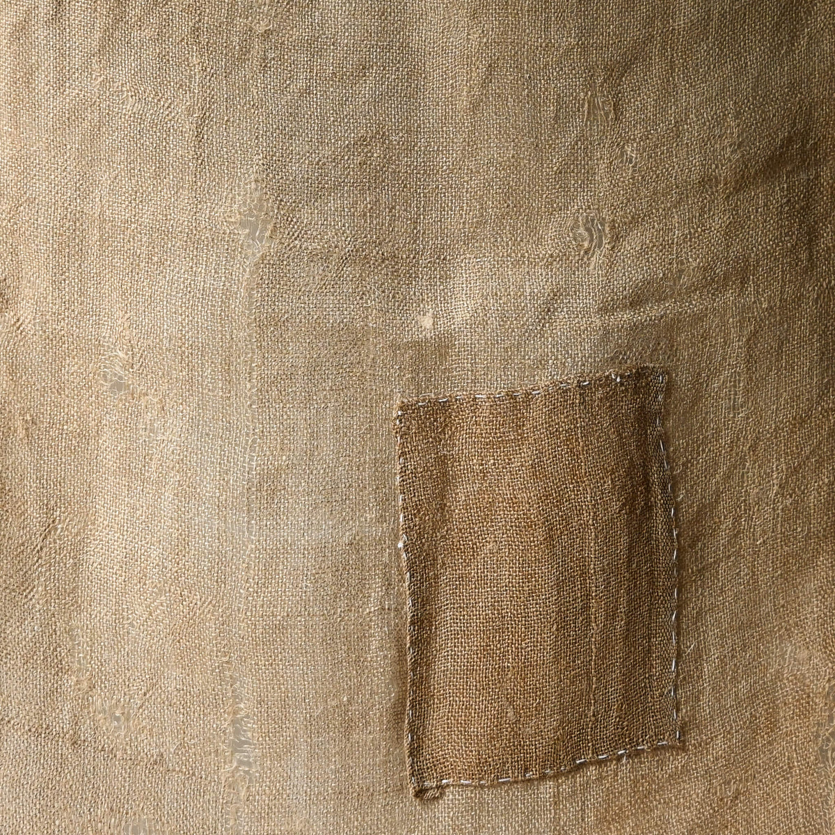 Detailed view of antique natural wide width hemp cloth with mends with rustic feel.
