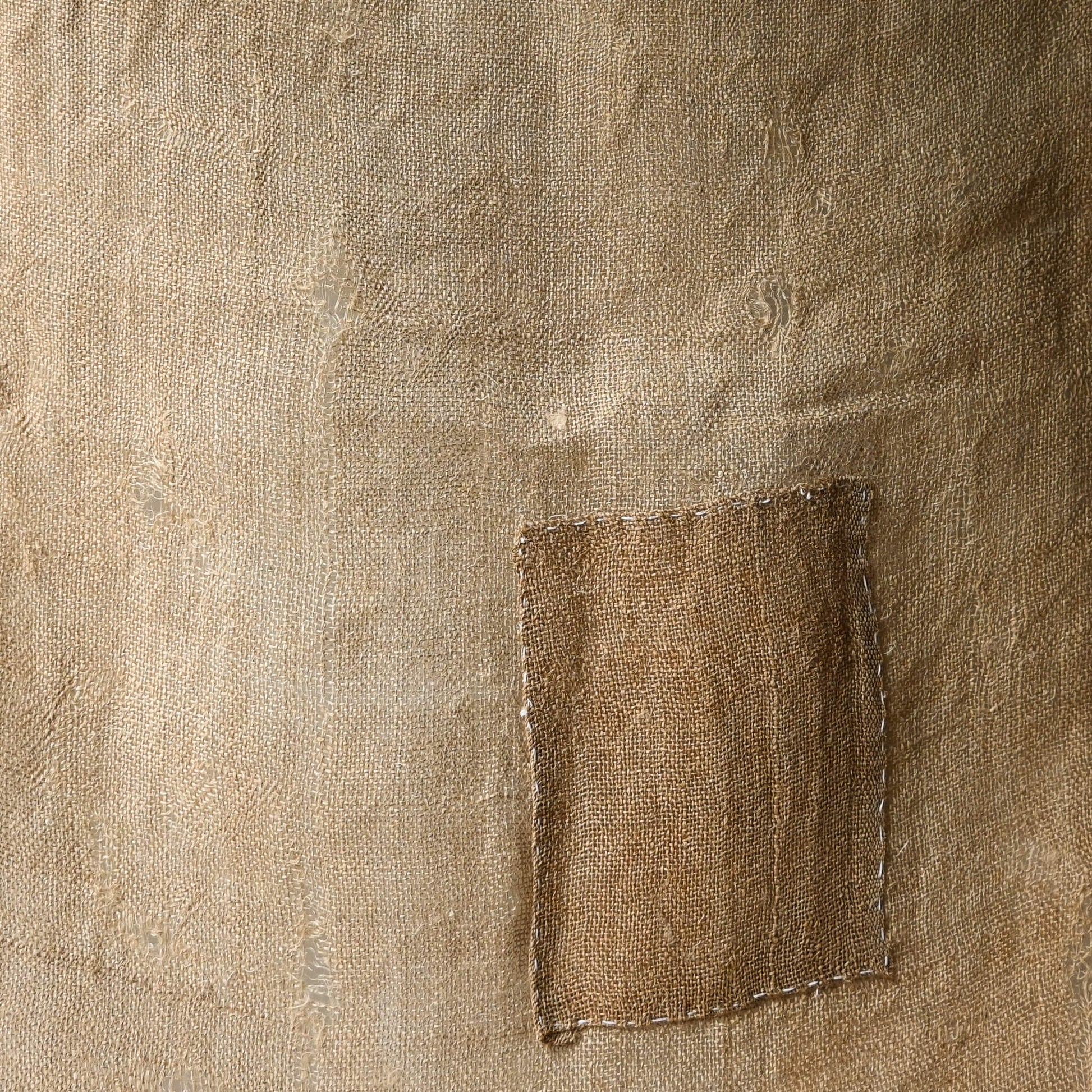 Detailed view of antique natural wide width hemp cloth with mends with rustic feel.