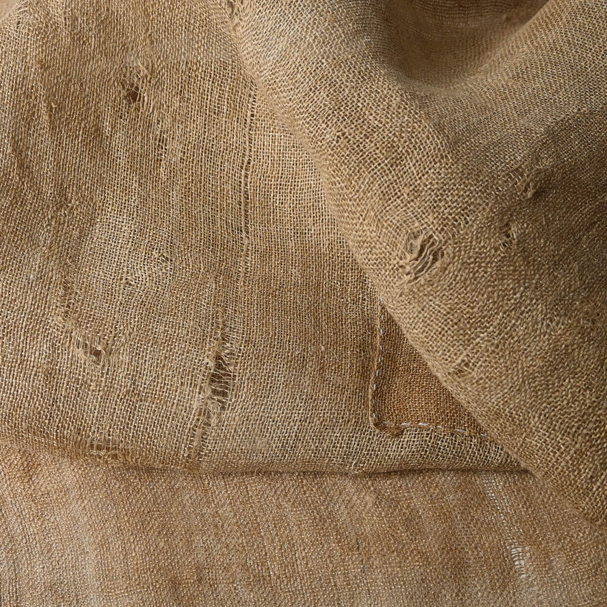 Detailed view of antique natural wide width hemp cloth with mends with rustic feel.