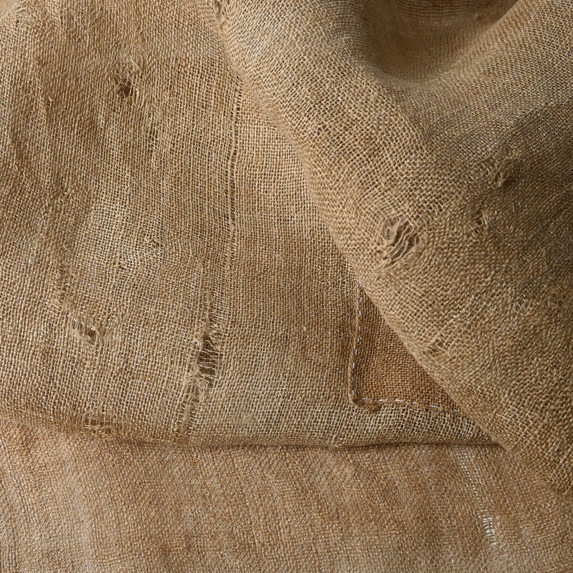 Detailed view of antique natural wide width hemp cloth with mends with rustic feel.