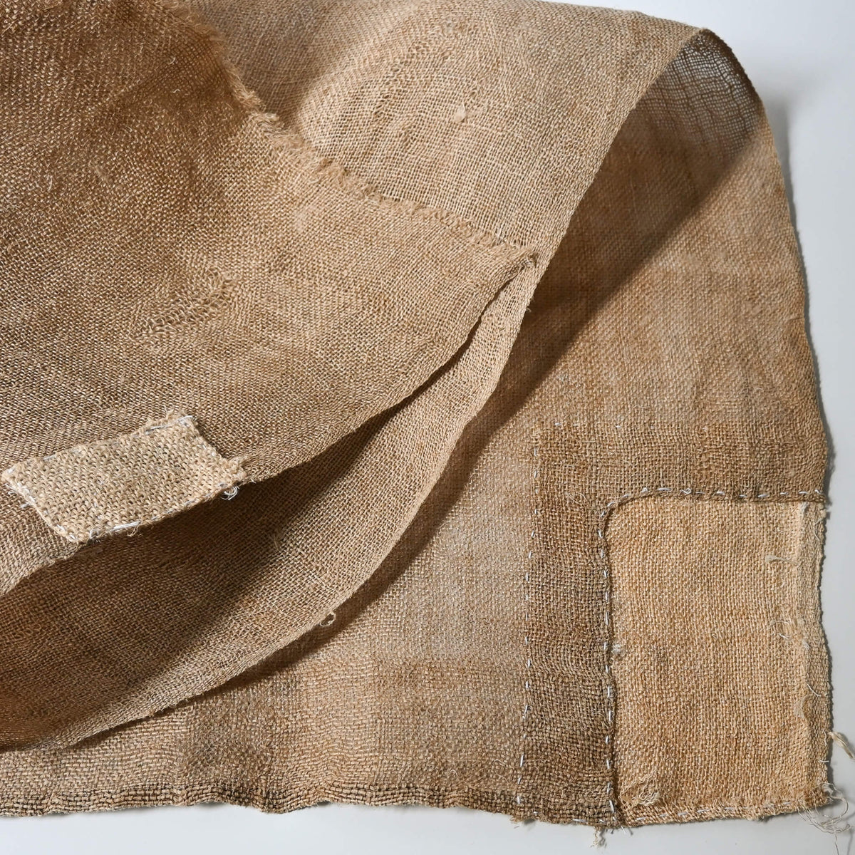 Detailed view of antique natural wide width hemp cloth with mends with rustic feel.