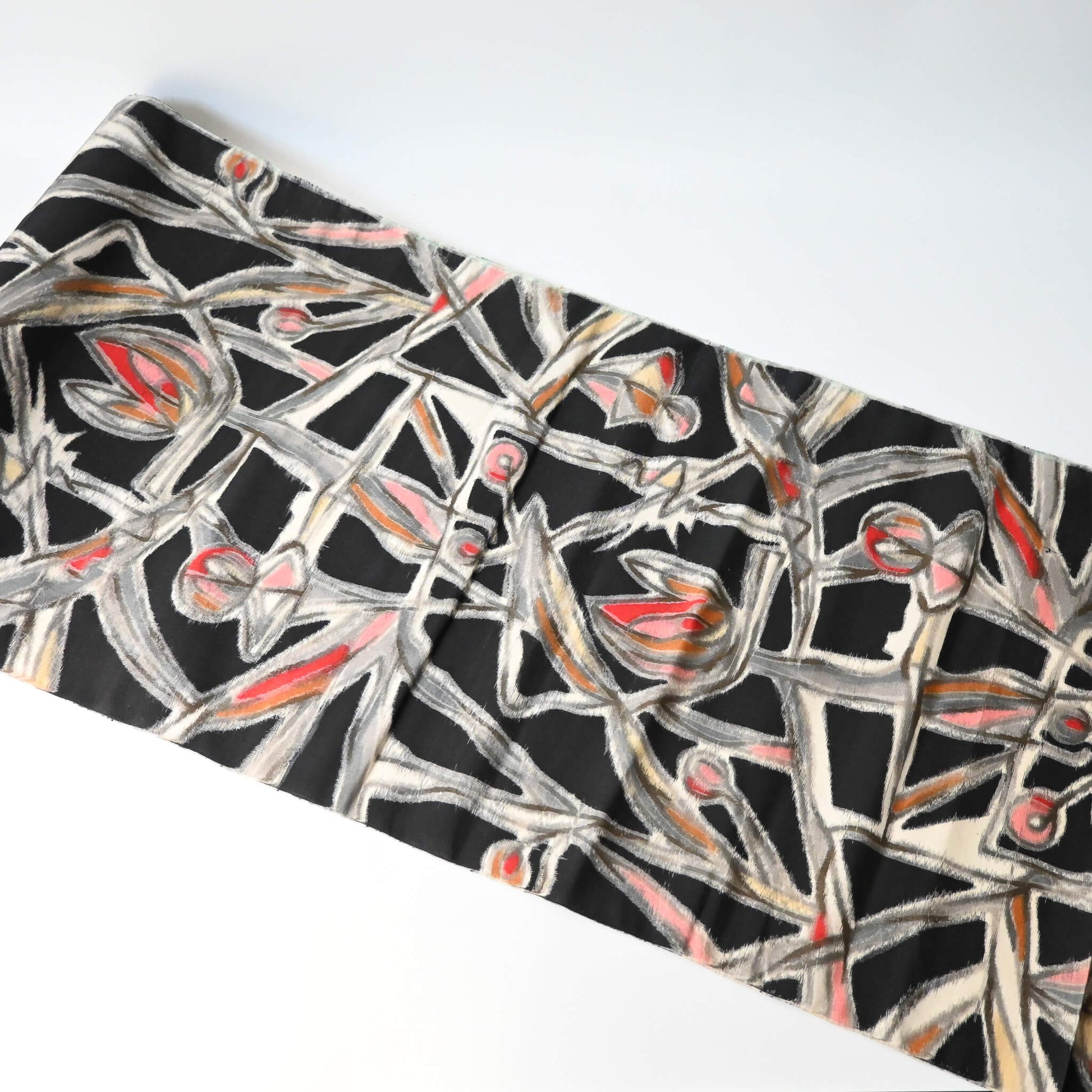 Wide view of vintage Meisen silk kimono fabric in black with pink and red cubism floral pattern.