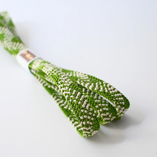 Close-up view of recycled silk obijime in a fresh matcha green with white accent.