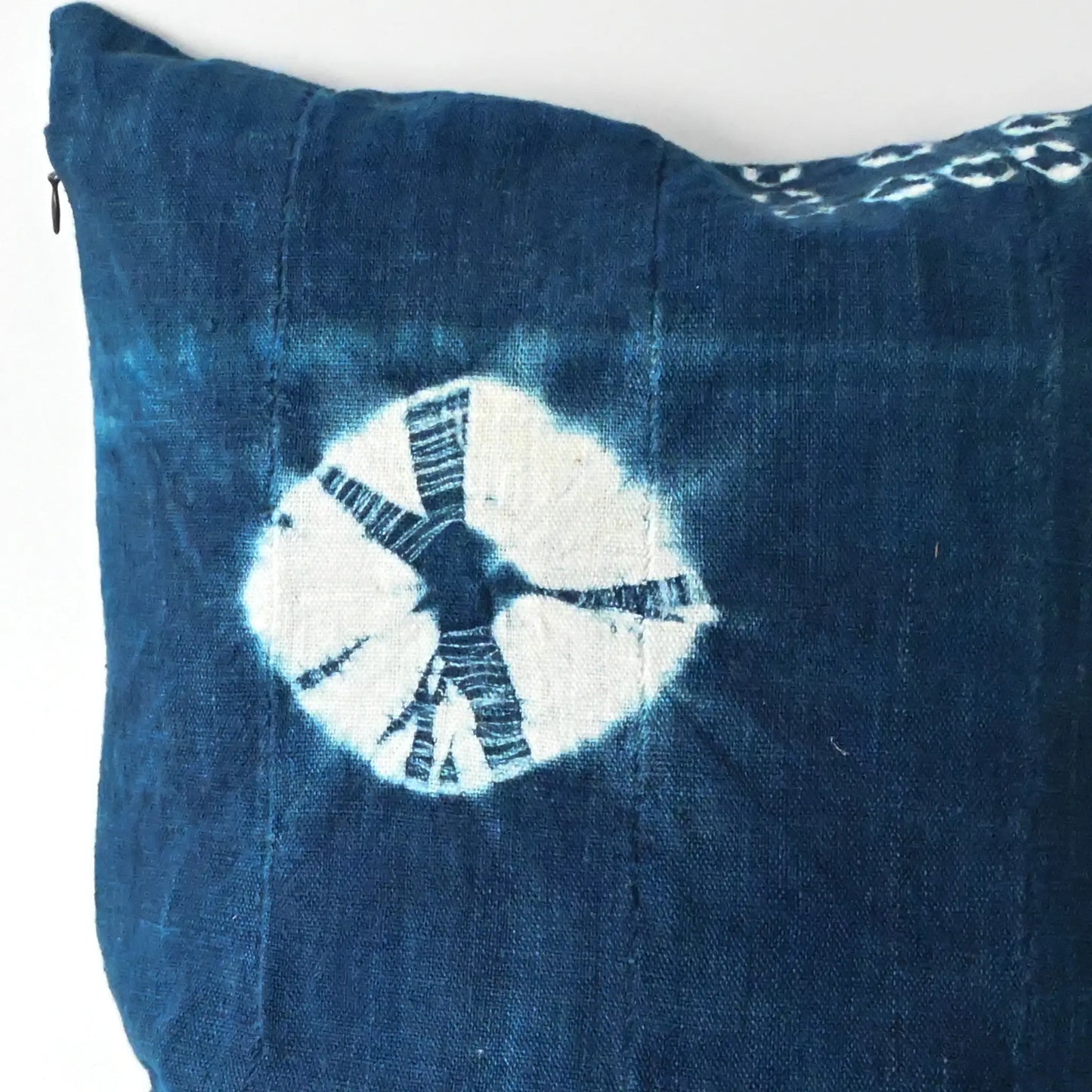 Close-up view of handmade shibori indigo African mudcloth cushion with duck feather insert.