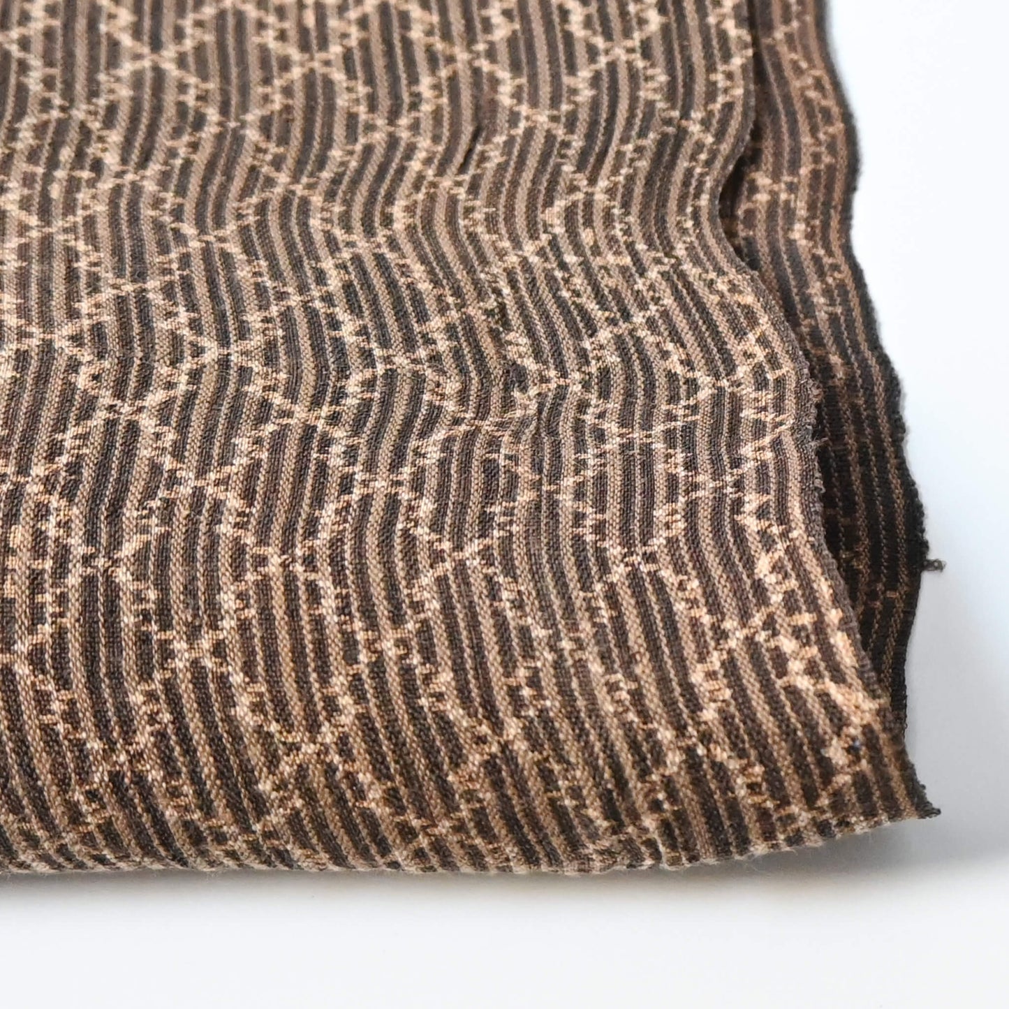 Close-up view of vintage collectable bashofu banana fibre textile fragment in rich brown with geometric pattern.