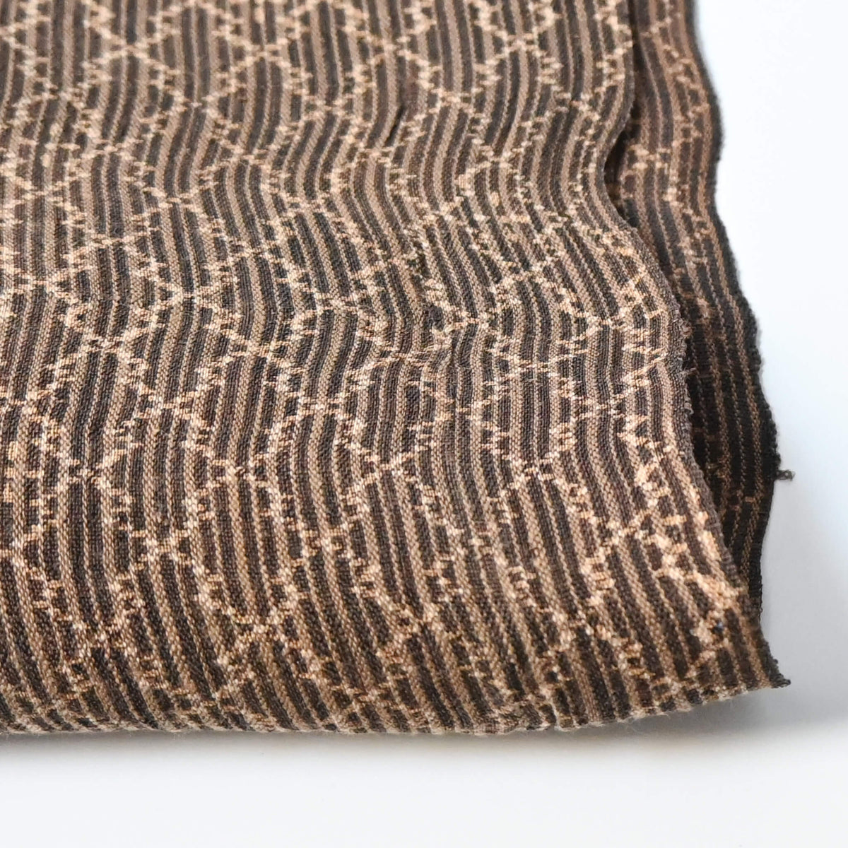 Close-up view of vintage collectable bashofu banana fibre textile fragment in rich brown with geometric pattern.