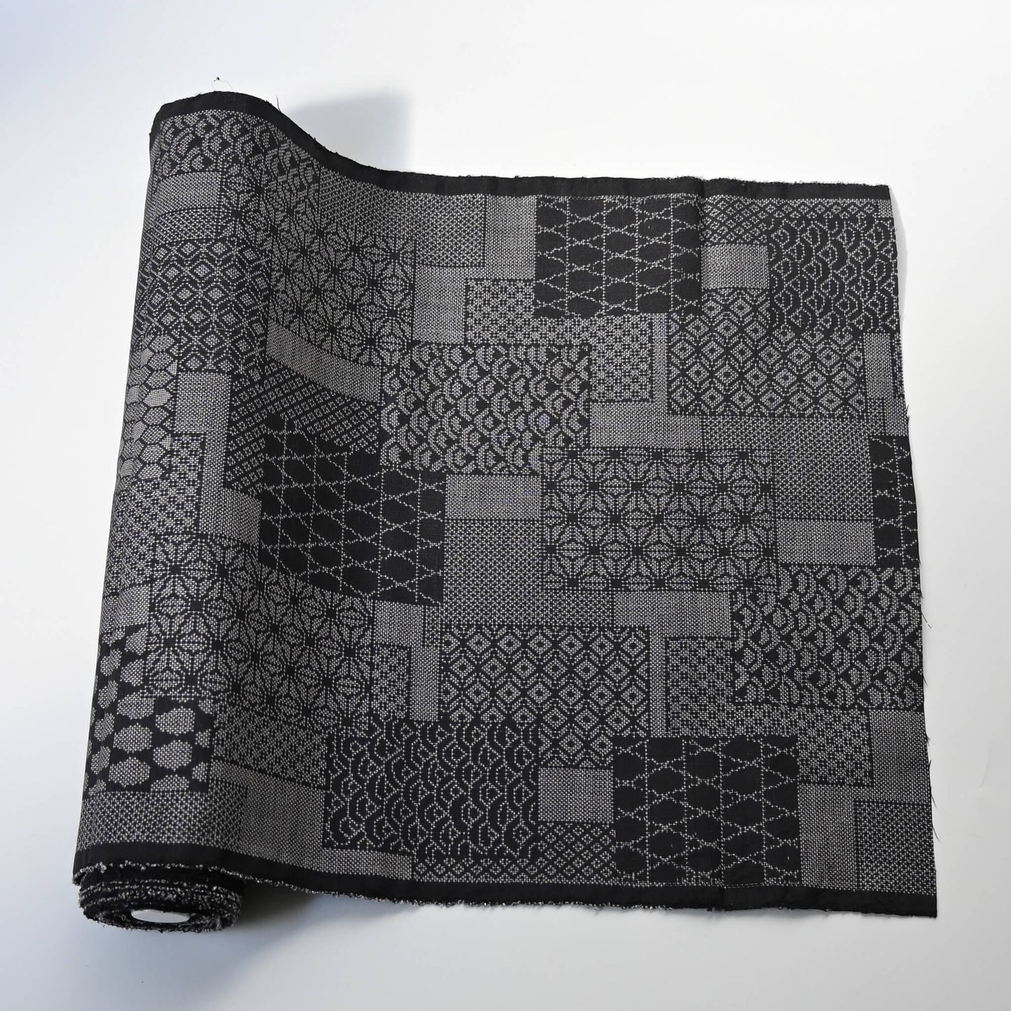 Vintage black silk kimono fabric roll with patchwork-style geometric pattern, sold by the metre.