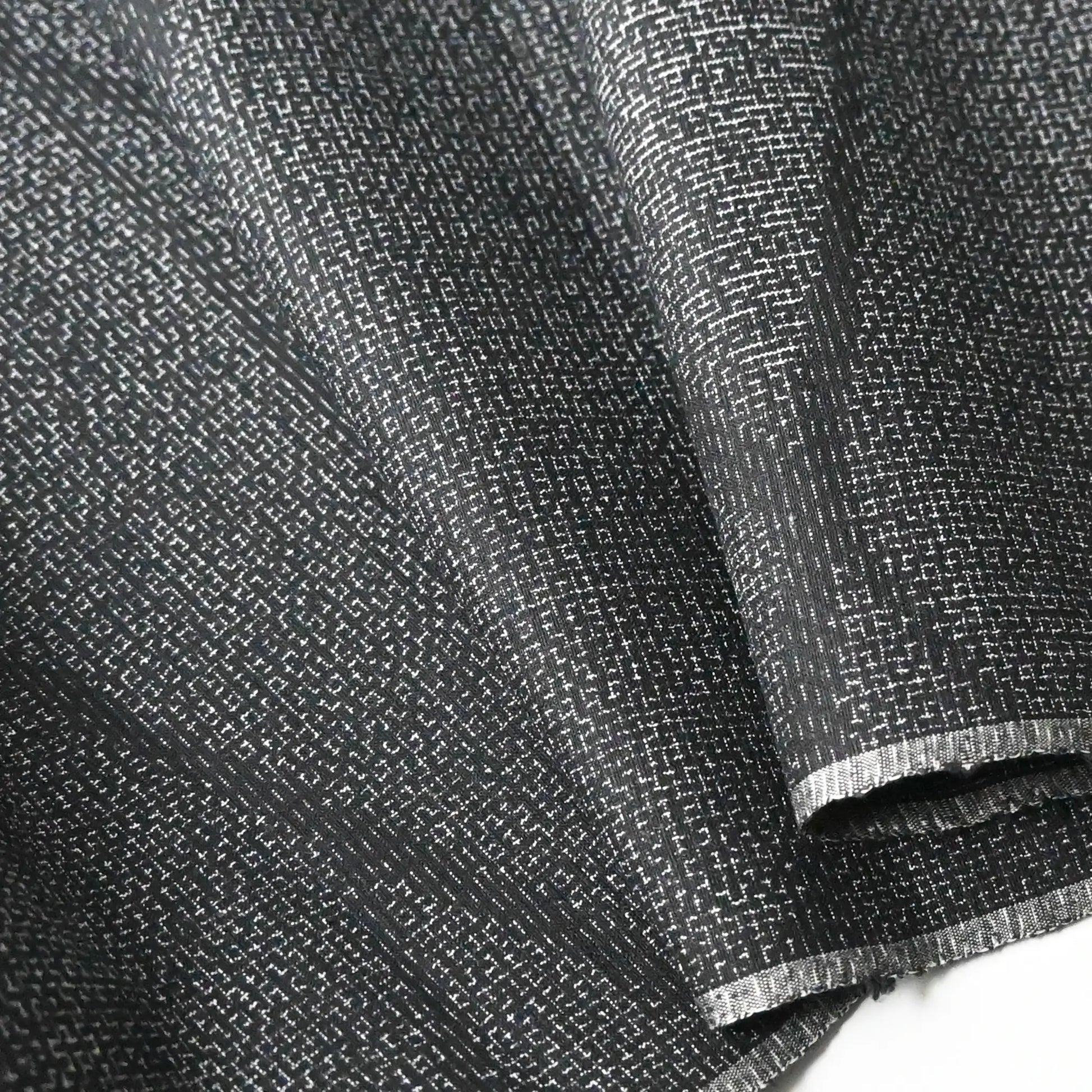 Detailed view of vintage black tsumugi silk kimono fabric roll with modern geometric pattern.