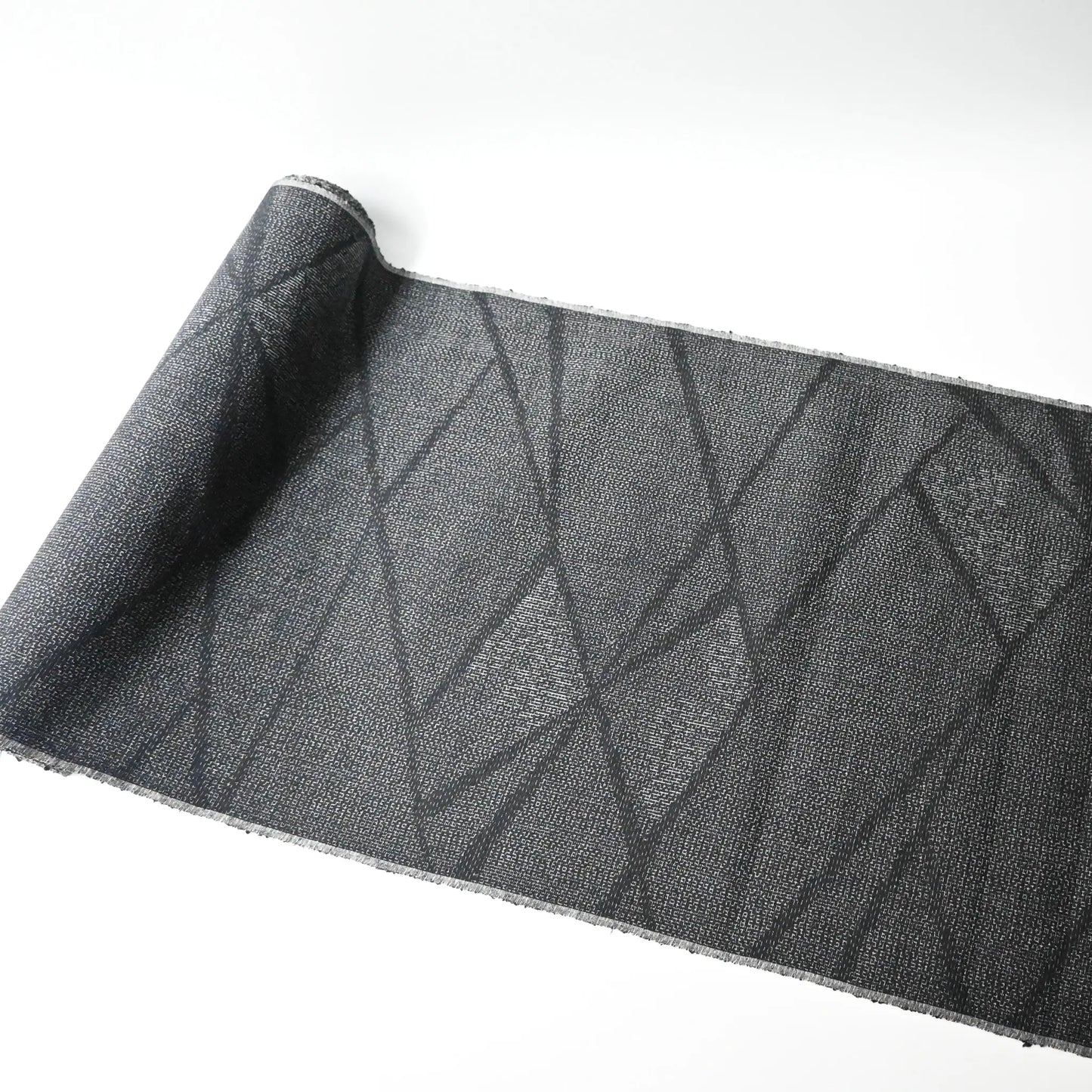 Full view of vintage black tsumugi silk kimono fabric roll with modern geometric pattern.