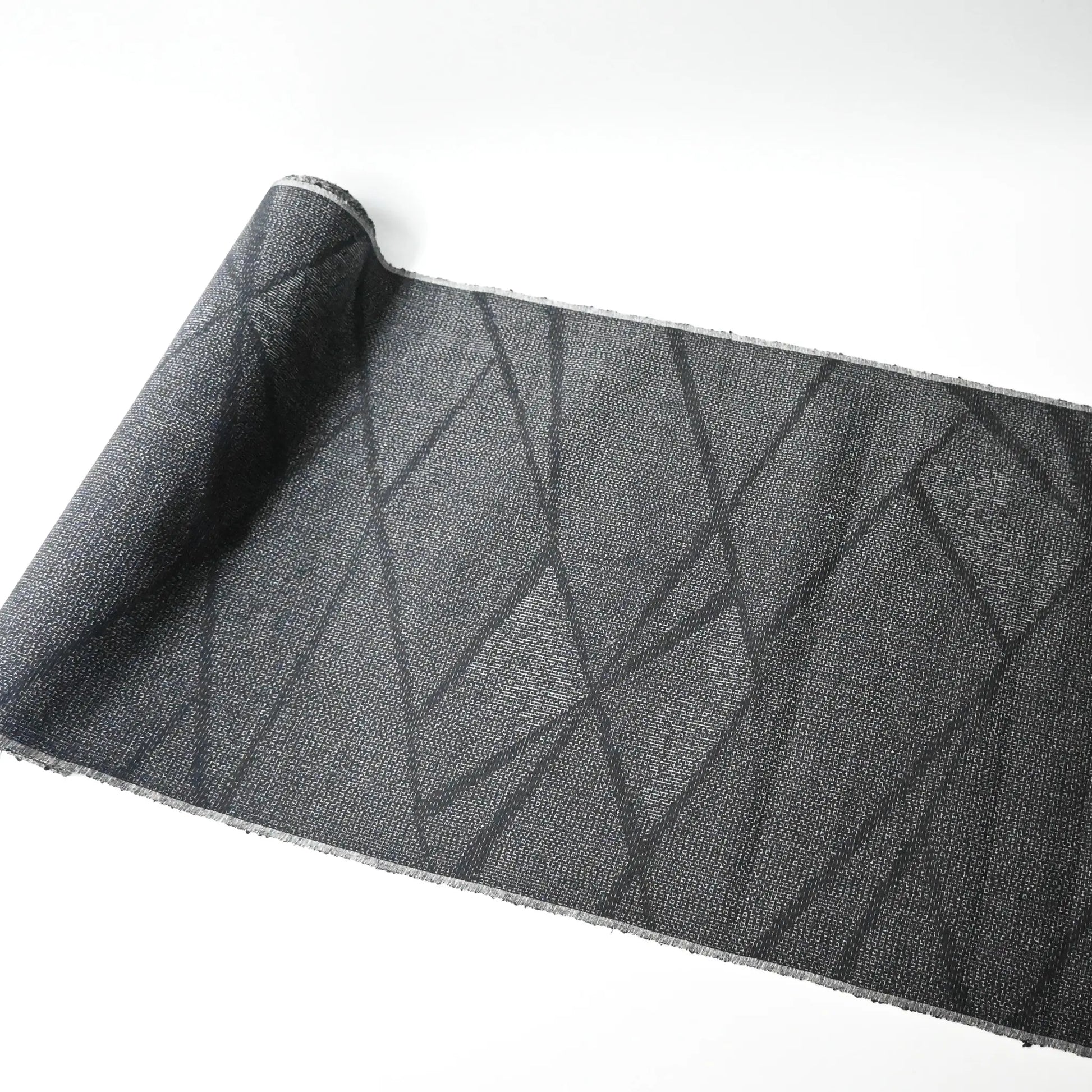 Full view of vintage black tsumugi silk kimono fabric roll with modern geometric pattern.