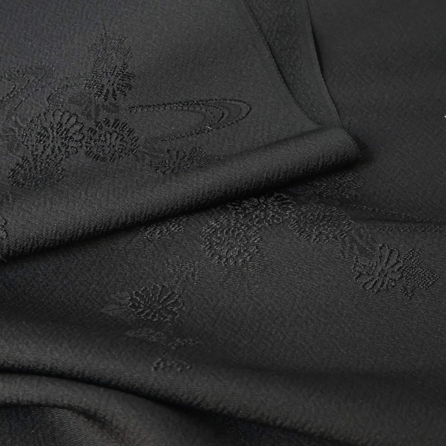 Close-up view of vintage black silk jacquard kimono fabric with running water and chrysanthemum motifs, drape well.