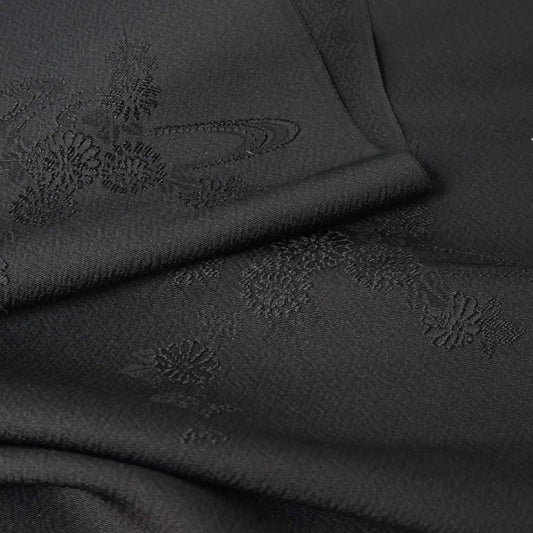 Close-up view of vintage black silk jacquard kimono fabric with running water and chrysanthemum motifs, drape well.