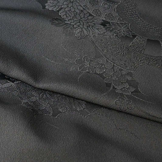 Close-up view of vintage Japanese black silk jacquard kimono fabric with floral motif, has a soft handle and drapes well.