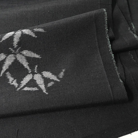 Close-up view of vintage Japanese tsumugi silk kimono fabric piece in black with small grey bamboo motif.